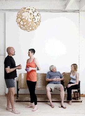 Clients and trainer chatting in the light-filled Movement Lab studio under a wooden pendant lamp